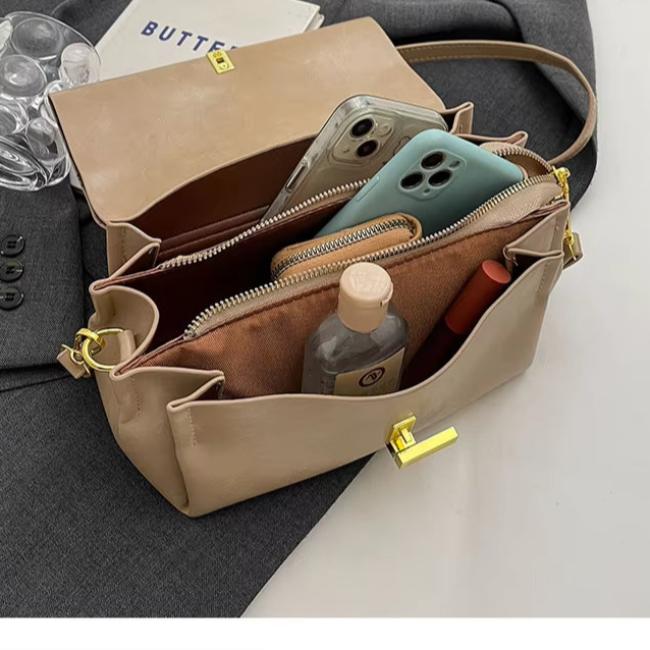 Borsa a tracolla beige in pelle con tasche aperte, contenente smartphone, bottiglia d'acqua, rossetto e portafoglio. Accessorio moda elegante.