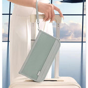 Donna con portafoglio da viaggio grigio su valigia bianca in aeroporto. Accessorio elegante, pratico per viaggi, con cinturino da polso.