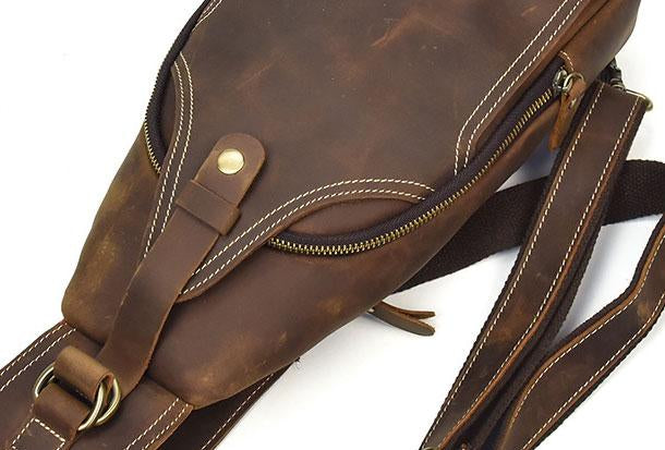 Zaino a tracolla in pelle marrone vintage, con cerniera e cuciture bianche, ideale per uomo e donna. Accessorio moda resistente e versatile.