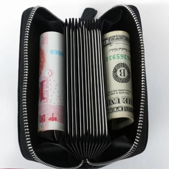 Portafoglio nero aperto con cerniera, contenente banconote di yuan e dollari USA. Design compatto, ideale per viaggi e organizzazione denaro.