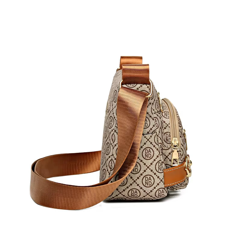 Borsa a tracolla beige con motivo monogramma, dettagli in pelle marrone, cerniera dorata e tracolla regolabile. Elegante accessorio moda donna.