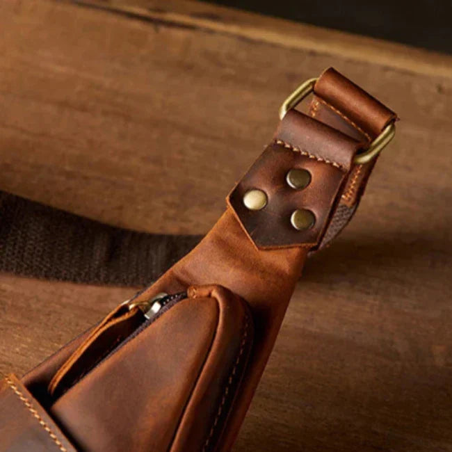 Cintura in pelle marrone con fibbia in metallo, dettagli in ottone e cuciture robuste su sfondo di legno. Accessorio moda elegante e resistente.