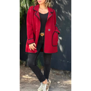 Cappotto rosso donna con bordi neri, abbinato a jeans neri e sneakers leopardate. Moda autunnale casual elegante.