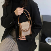 Donna con borsa a tracolla marrone e beige, design elegante, abbigliamento nero, moda autunno, accessorio femminile, stile casual chic.