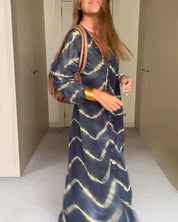 Abito lungo donna a righe ondulate blu e beige, maniche lunghe, borsa a tracolla marrone. Moda femminile, stile casual chic, tendenze 2023.