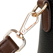 Gancio in metallo dorato su borsa in pelle marrone e nera, dettaglio di alta qualità, accessorio moda elegante, chiusura sicura e resistente.
