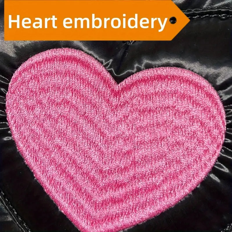 Ricamo a forma di cuore rosa su tessuto nero lucido, dettaglio moda, design elegante, accessorio abbigliamento, stile contemporaneo.