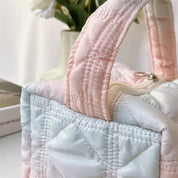 Borsa trapuntata in raso rosa e bianco, manici imbottiti, design elegante. Perfetta per moda femminile, accessorio chic e versatile.