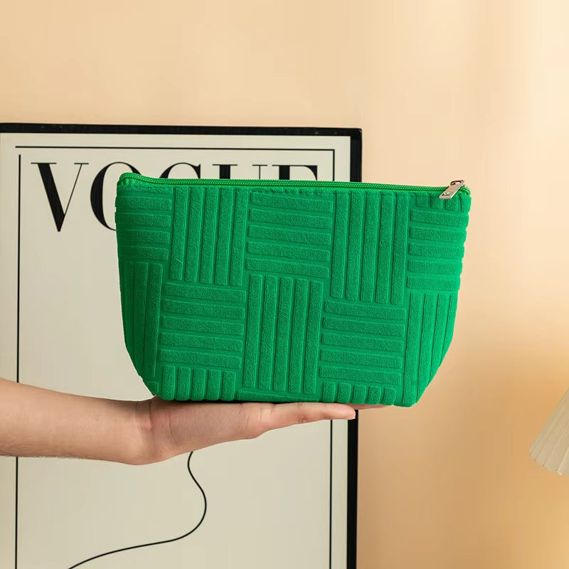 Pochette verde con motivo geometrico, chiusura a zip, tenuta in mano. Accessorio moda elegante, ideale per organizzare cosmetici e piccoli oggetti.