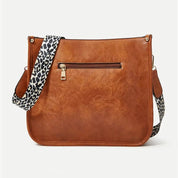 Borsa a tracolla in pelle marrone con cerniera frontale e cinturino leopardato. Elegante e pratica, perfetta per moda donna e accessori.