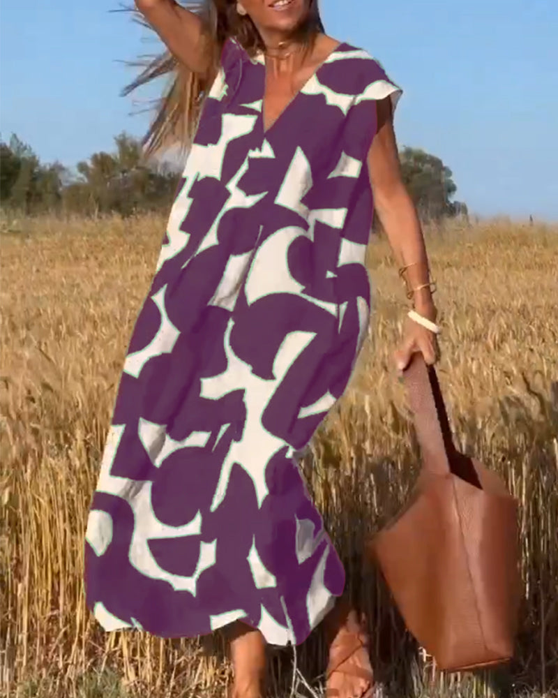 Donna in abito estivo viola con motivi bianchi, in un campo di grano, borsa marrone, giornata soleggiata. Moda estiva, abbigliamento casual.