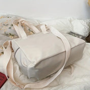 Borsa a tracolla beige in tessuto, design minimalista, manici robusti, ideale per viaggi e uso quotidiano. Accessorio moda versatile e pratico.