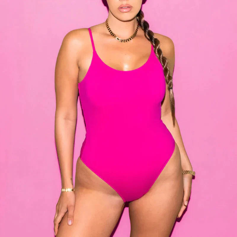 Costume intero rosa acceso su sfondo rosa, donna con treccia e gioielli dorati. Moda mare, abbigliamento estivo, tendenze beachwear.