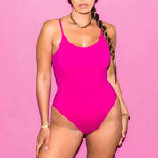 Costume intero rosa acceso su sfondo rosa, donna con treccia e gioielli dorati. Moda mare, abbigliamento estivo, tendenze beachwear.