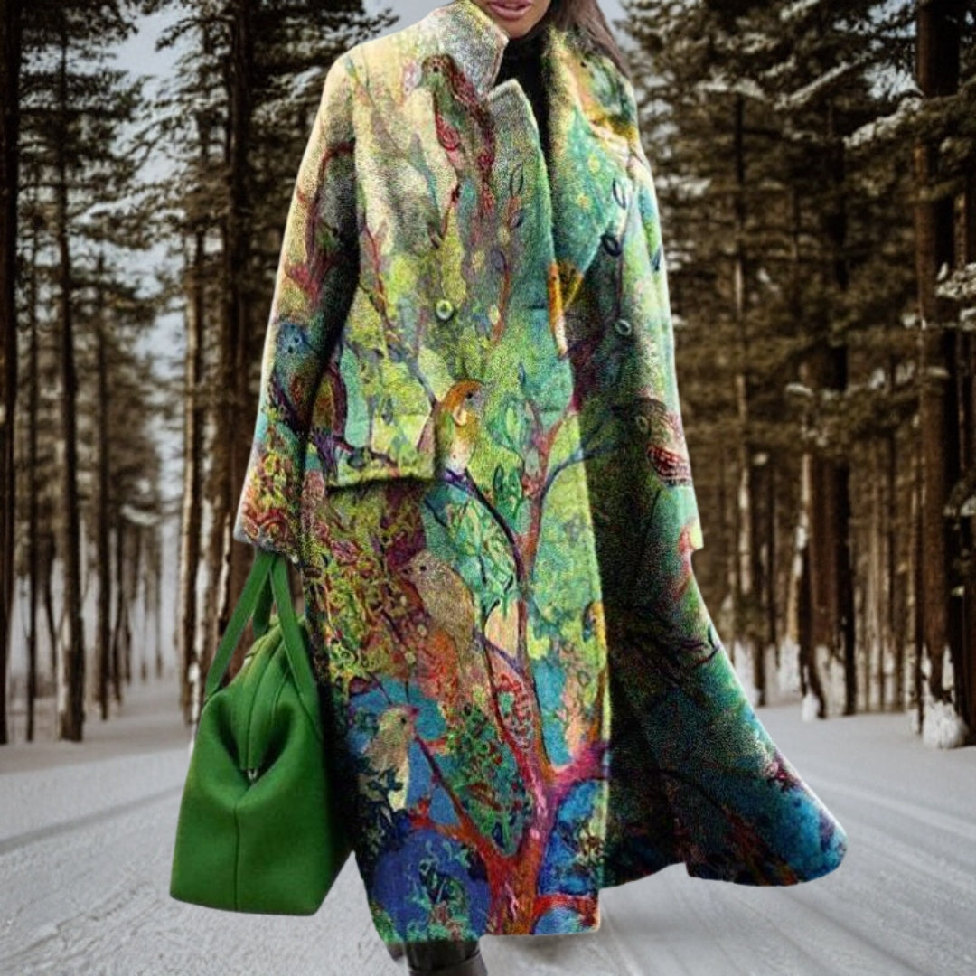Cappotto invernale colorato con motivi artistici di uccelli e alberi, borsa verde, foresta innevata sullo sfondo. Moda donna, abbigliamento artistico.