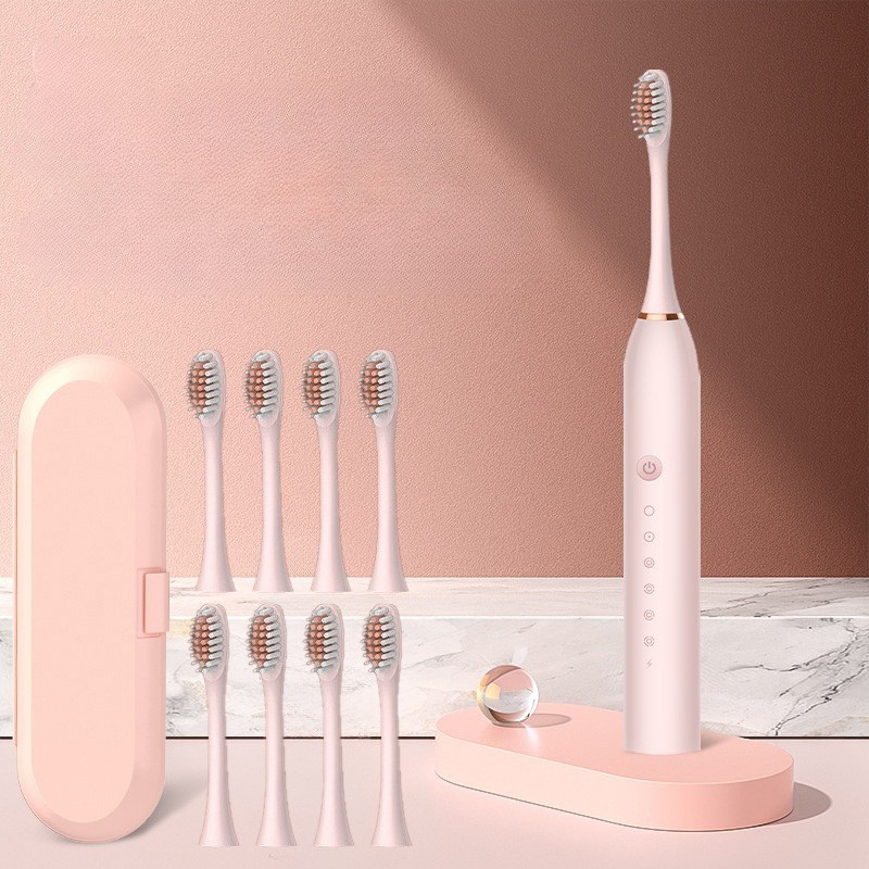 Spazzolino elettrico rosa con base di ricarica, otto testine di ricambio e custodia da viaggio. Design elegante, ideale per igiene orale quotidiana.