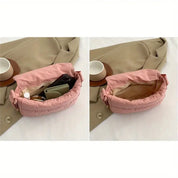 Borsa a tracolla rosa imbottita aperta su cappotto beige, contenente portafoglio, smartphone e cosmetici. Accessorio moda donna elegante e pratico.