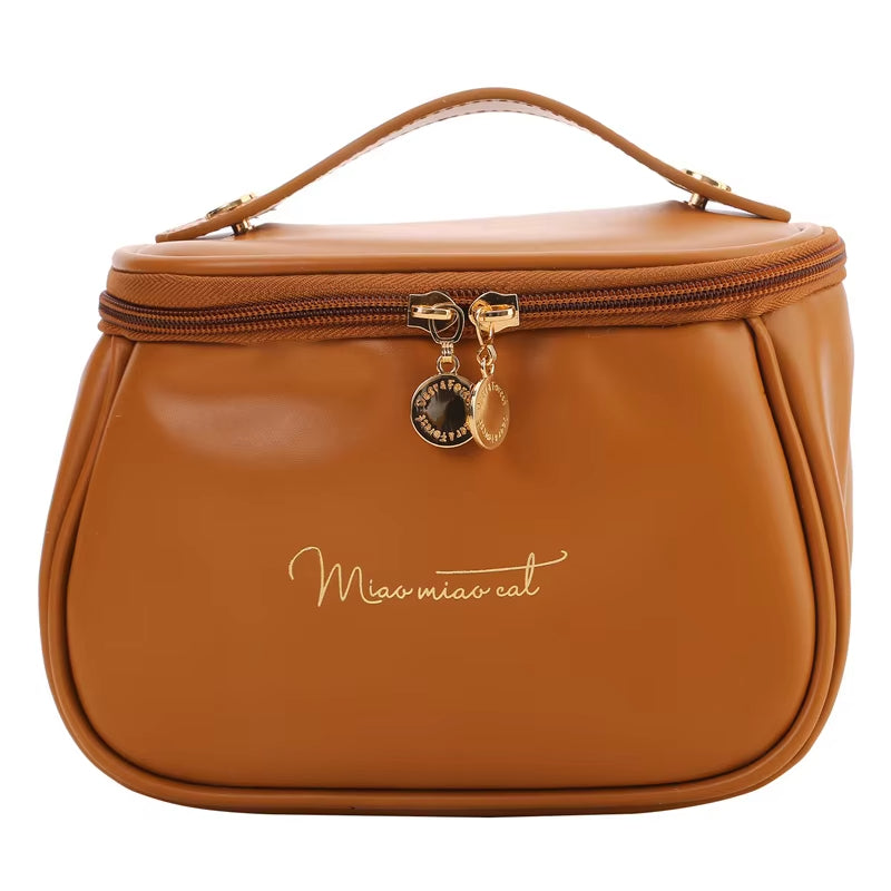 Borsa cosmetica marrone in pelle PU con cerniera dorata e manico superiore, design elegante, ideale per viaggi e organizzazione trucco.