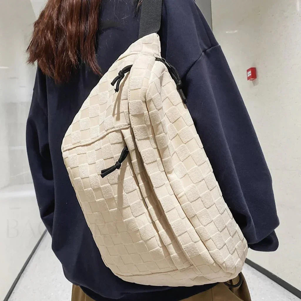 Zaino a tracolla beige intrecciato su persona con felpa nera. Design moderno, tessuto elegante, ideale per moda urbana e viaggi.
