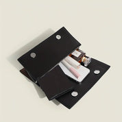 Portafoglio nero in pelle aperto con smartphone, rossetto, profumo e accessori. Design elegante, ideale per moda e accessori donna.