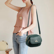 Donna con borsa a tracolla verde in pelle, indossa top rosa e jeans. Accessorio moda elegante, perfetto per look casual e chic.