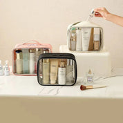 Borse trasparenti per cosmetici su tavolo da bagno, contenenti prodotti di bellezza e skincare. Ideali per organizzare trucchi e accessori da viaggio.