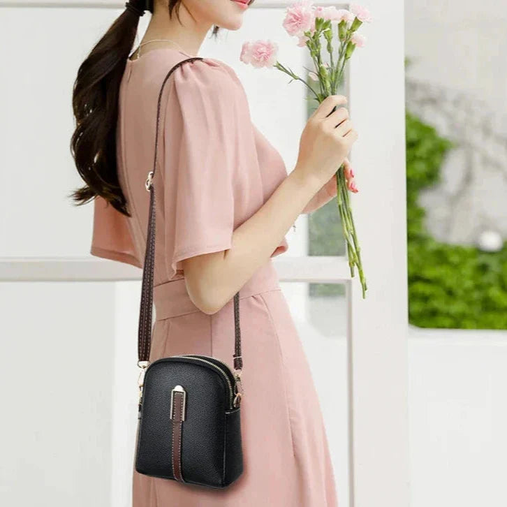 Donna in abito rosa con borsa a tracolla nera e fiori rosa. Accessori moda eleganti, stile femminile, tendenze borse 2023.