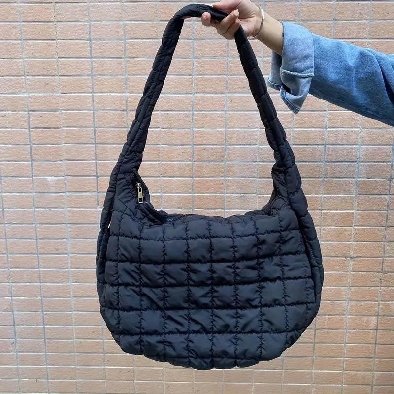 Borsa a spalla trapuntata nera, design moderno, manico imbottito, chiusura con zip, ideale per moda casual e shopping.