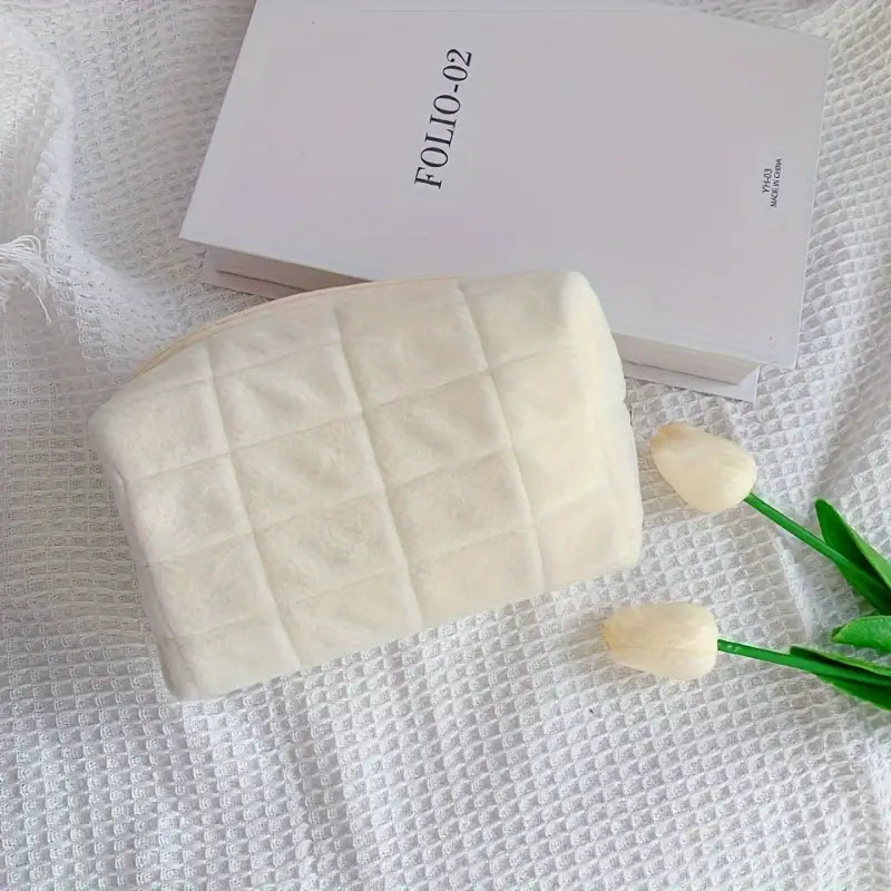 Pochette trapuntata bianca su coperta a trama, con libro "Folio 02" e tulipani bianchi. Accessorio moda elegante, ideale per ogni occasione.