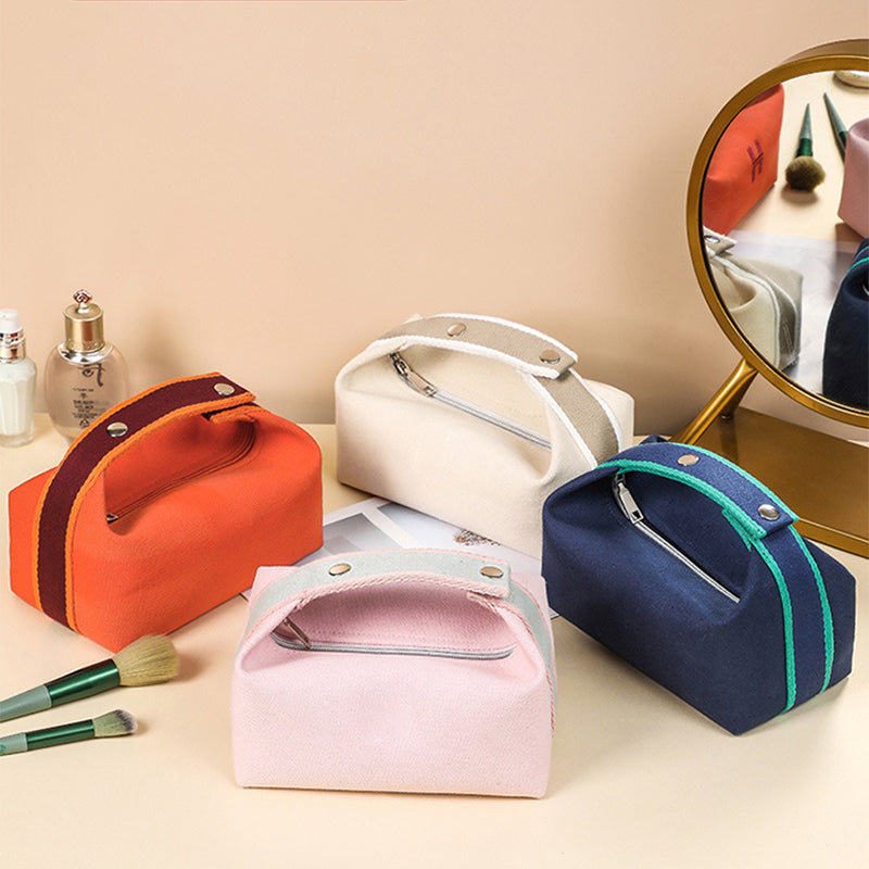 Quattro astucci da trucco in tessuto colorato su tavolo da toeletta con specchio, pennelli e profumo. Design elegante e pratico per cosmetici.