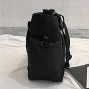 Zaino nero minimalista su sfondo bianco, design moderno con tasca frontale e chiusura a cordoncino. Ideale per viaggi e uso quotidiano.
