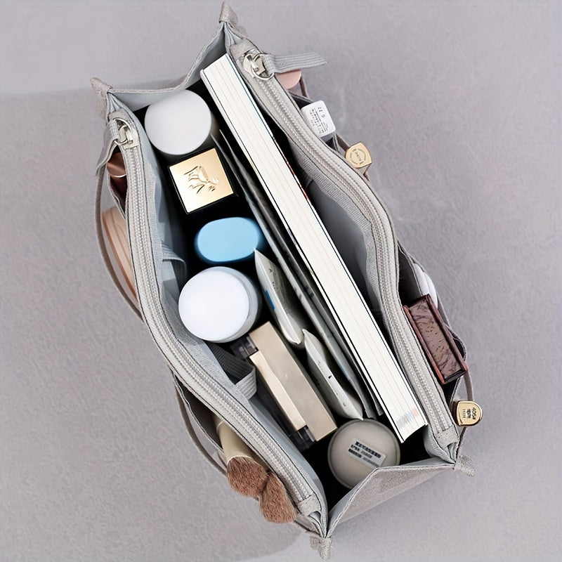Borsa organizer grigia aperta vista dall'alto, contenente cosmetici, libri e accessori. Ideale per organizzazione e viaggio.
