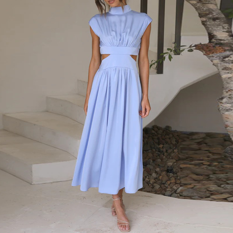 Abito lungo azzurro con tagli laterali, senza maniche, indossato da una donna su scale bianche. Elegante e moderno, perfetto per eventi estivi.
