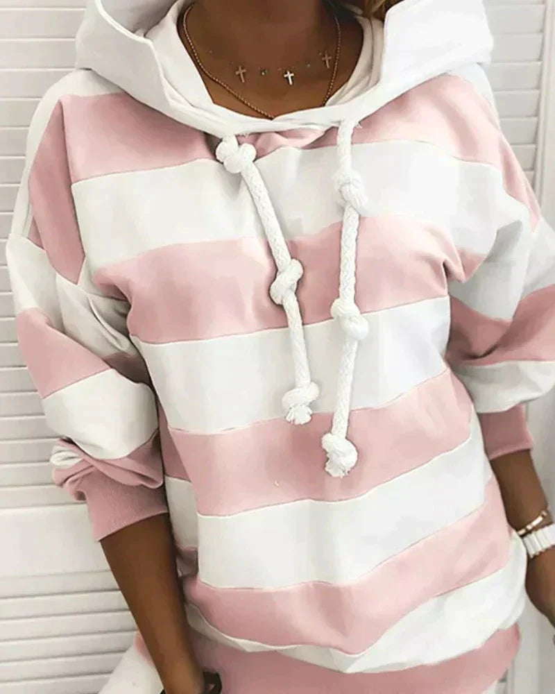 Felpa a righe rosa e bianche con cappuccio e lacci, indossata da una persona. Moda casual, abbigliamento donna, stile autunnale.