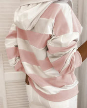 Felpa a righe rosa e bianche con cappuccio, indossata da una persona di spalle. Design casual, moda autunnale, abbigliamento donna.