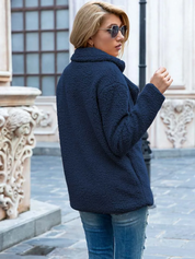 Donna con giacca in pile blu scuro, jeans strappati, occhiali da sole, in strada urbana. Moda autunnale, abbigliamento casual donna.