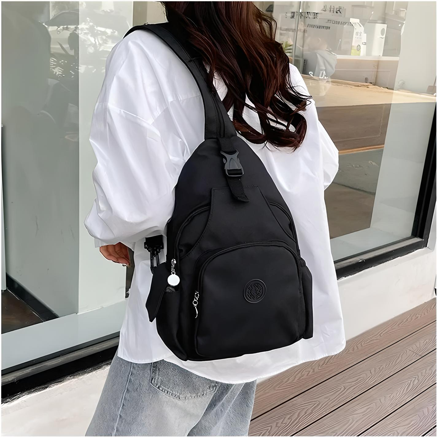 Donna con zaino nero a tracolla, indossa camicia bianca e jeans. Zaino casual, moda urbana, accessorio pratico per viaggi e quotidiano.