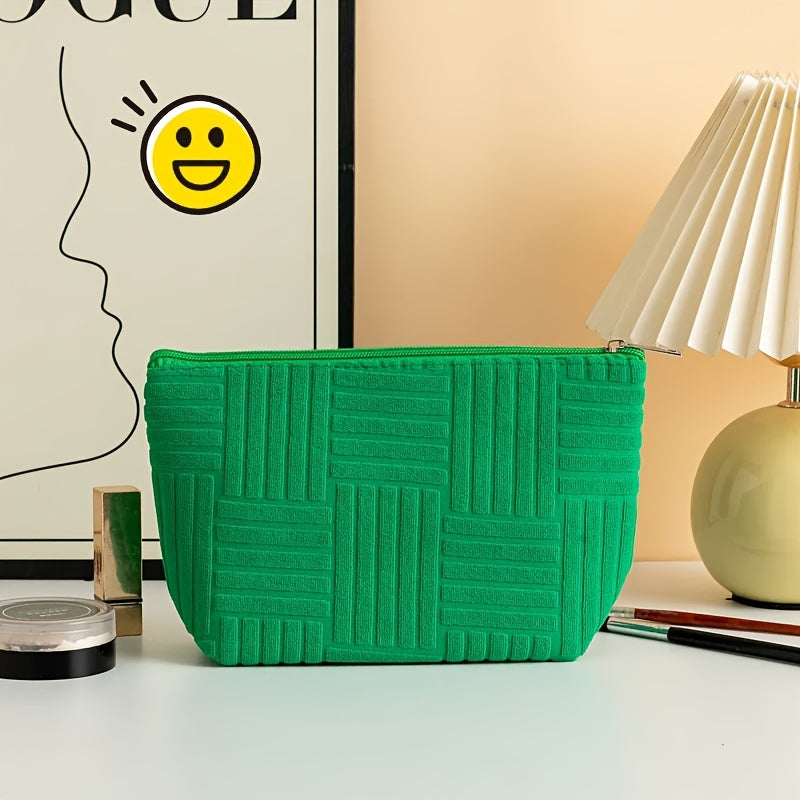 Pochette verde con motivo geometrico, posizionata su scrivania con lampada moderna e poster artistico. Accessorio moda elegante e versatile.