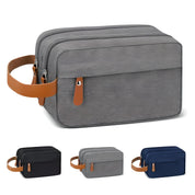 Borsa da toilette grigia con manico in pelle marrone, doppia cerniera, tasca frontale. Disponibile in vari colori: nero, grigio, blu.