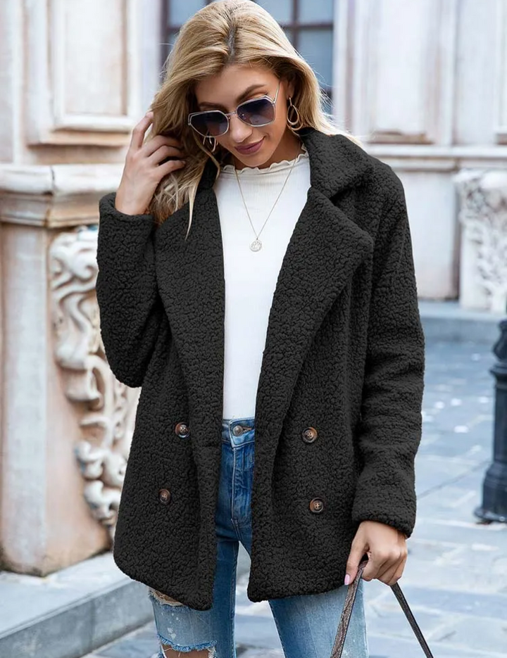 Donna con cappotto nero in pile, occhiali da sole, jeans strappati e maglia bianca. Moda autunnale, abbigliamento casual elegante.