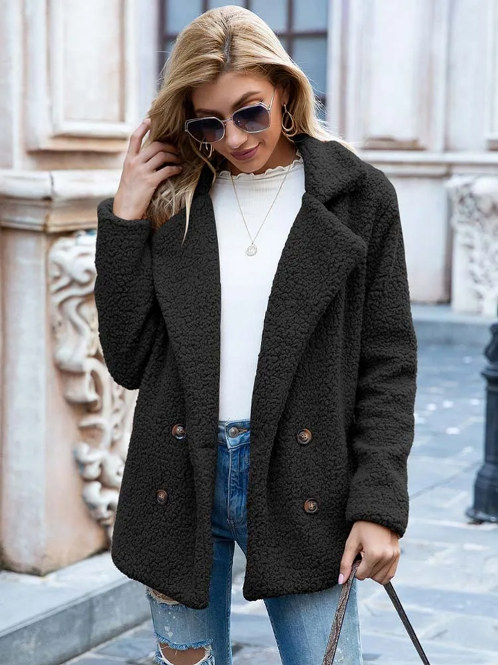 Donna con cappotto nero in pile, occhiali da sole, jeans strappati e maglia bianca. Moda autunnale, abbigliamento casual elegante.