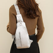 Zaino monospalla argento metallizzato con tracolla regolabile a zigzag, indossato da donna con maglione marrone. Accessorio moda elegante e pratico.