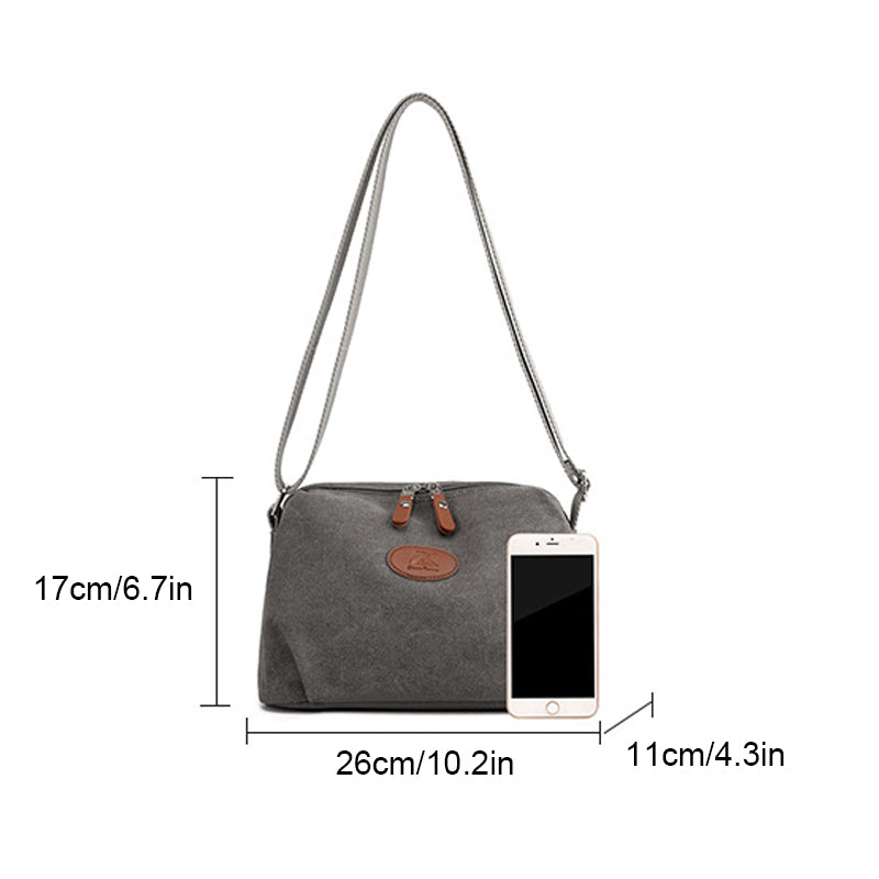 Borsa a tracolla grigia in tessuto, dimensioni 26x17x11 cm, con zip e tasca frontale, accanto a smartphone per confronto grandezza.