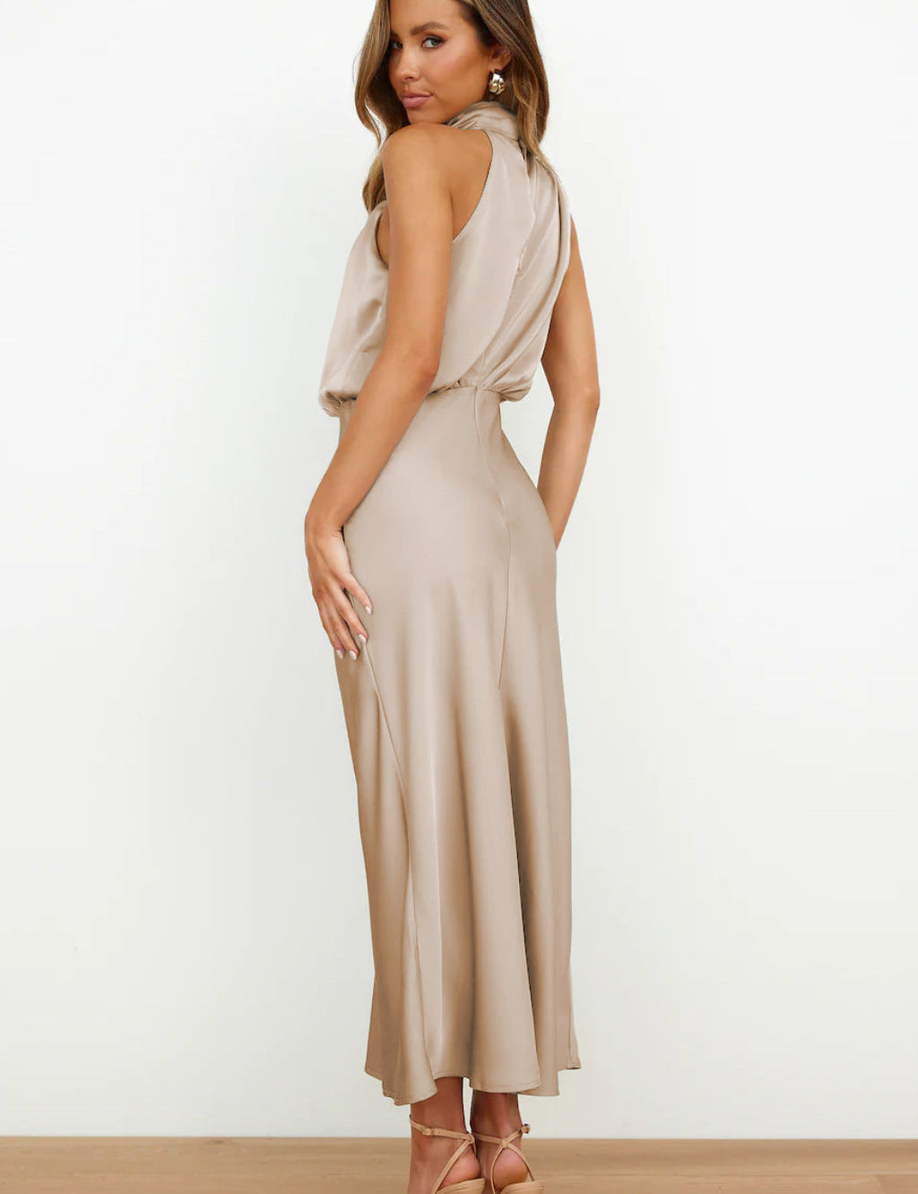 Abito lungo elegante in raso beige, senza maniche, con scollo a V e schiena scoperta. Perfetto per eventi formali e serate speciali.