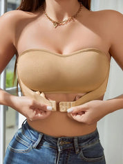 Donna indossa reggiseno senza spalline beige, chiusura frontale, abbinato a jeans. Intimo femminile, moda estiva, comfort quotidiano.