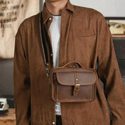 Borsa a tracolla in pelle marrone da uomo, elegante e pratica, indossata su camicia marrone. Accessorio moda maschile, stile casual.