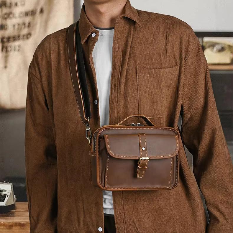Borsa a tracolla in pelle marrone da uomo, elegante e pratica, indossata su camicia marrone. Accessorio moda maschile, stile casual.