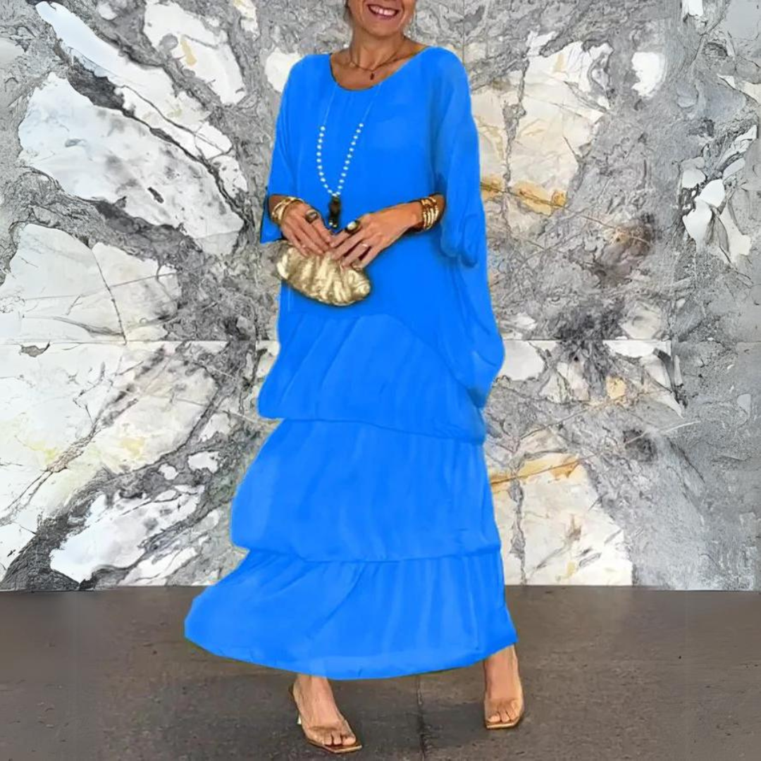 Abito lungo blu elegante, donna con borsa dorata e sandali, sfondo marmo. Moda femminile, abbigliamento estivo, stile sofisticato.
