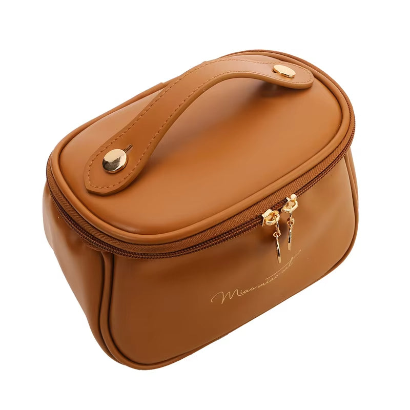 Borsa cosmetica marrone in pelle sintetica con manico, chiusura a zip dorata, design elegante. Ideale per trucco e accessori da viaggio.