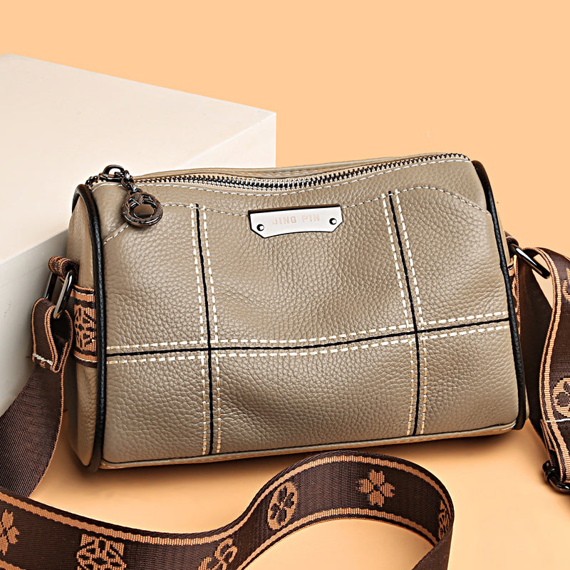 Borsa a tracolla in pelle marrone chiaro con cuciture bianche, cerniera superiore e tracolla regolabile con motivo floreale. Elegante e versatile.